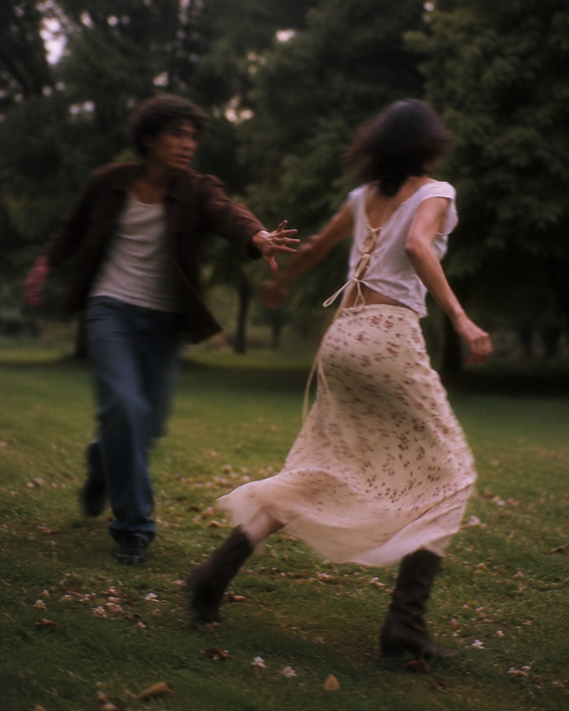 Two figures running hand in hand at dusk